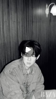 black and white photo of a boy in a denim jacket sitting at a table with a laptop