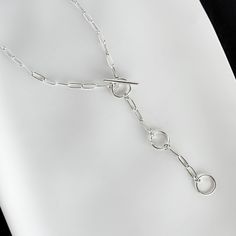 Elevate your everyday look with this handcrafted Paperclip Chain Toggle Necklace. The unique toggle clasp adds a touch of modern charm, while the adjustable length allows for versatile styling options. Made from high-quality sterling silver, this necklace is the perfect addition to your jewelry collection. Details: Chain: Solid Sterling Silver Paperclip Chain, 3mm Clasp: Handcrafted Sterling Silver toggle clasp, adjustable length Sizes: 16 inches to 24 inches Shipping: Ready to ship within one b Silver Lariat Toggle Necklace, Silver Metal Lariat Toggle Necklace, Modern Metal Toggle Necklace, Silver Lariat Toggle Necklace Gift, Modern Link Chain Necklace With Toggle Clasp, Modern Chain Link Necklace With Toggle Clasp, Classic Silver Toggle Necklace With Adjustable Chain, Everyday Toggle Link Necklace, Everyday Link Toggle Necklace