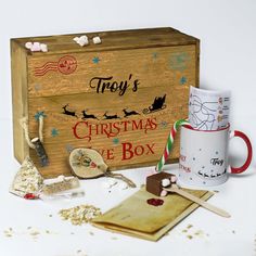 a wooden box filled with christmas items next to a coffee mug and candy canes