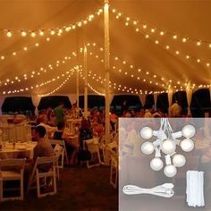 the inside of a tent with lights strung from it and people sitting at tables under them