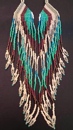 a necklace with beads and fringes hanging from it's side on a black surface