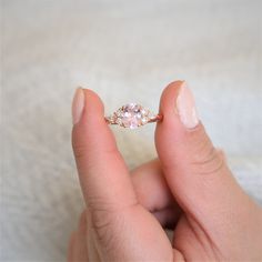 a woman's hand holding an engagement ring with two diamonds on top of it