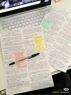 an open laptop computer sitting on top of a desk covered in paper and sticky notes