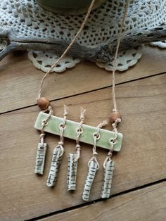 three pieces of pottery hanging from twine on a wooden table next to a potted plant