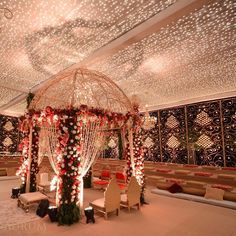 an indoor wedding venue decorated with white and red flowers, lights and chandeliers