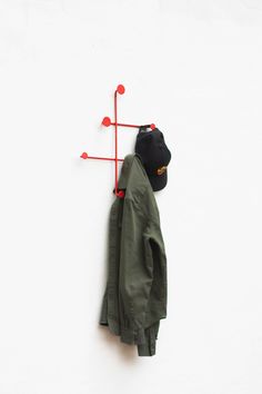 a coat hanging on the wall with two red pins sticking out of it's back