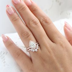 a woman's hand with a diamond ring on top of her finger and pink manicured nails