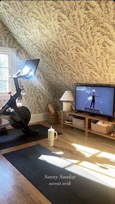 a living room with a television and exercise equipment on the floor in front of it