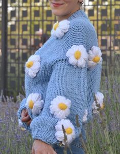 a woman wearing a blue sweater with flowers on it