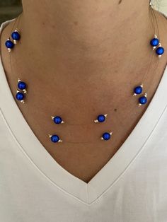 This is a beautiful double strand necklace made with the stunning blue miracle beads.  The necklace is a pretty delicate necklace with a floating bead effect. The beads are 8mm blue miracle beads. These beads are a mesmerising blue which show a 3d effect and stunning shine. Either side of the blue beads there are 2mm silver plated beads which compliment the blue perfectly. The beads are spaced along tiger tail wire. The shortest strand is 45 cm in length and the longest strand is 50 cm in length. The necklace fastens by way of a lobster clasp and ring.  Lead and Nickle free.  The necklace is packaged and wrapped in a pink Sugar and Spice gift box making the perfect and special gift.  Thanks for looking in my shop! Blue Beaded Necklace With Tiny Beads For Party, Blue Beaded Necklaces With Tiny Beads For Party, Blue Beaded Necklace For Party, Blue Party Beaded Necklace With Tiny Beads, Party Jewelry With Tiny Blue Beads, Blue Polished Beads Necklaces For Party, Blue Double Strand Pearl Necklace Gift, Blue Double Strand Pearl Necklace For Gift, Blue Polished Beads Necklace For Party