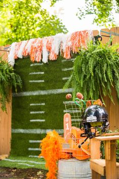 an orange and black football themed party with decorations on the sidelines, grass wall and wooden table