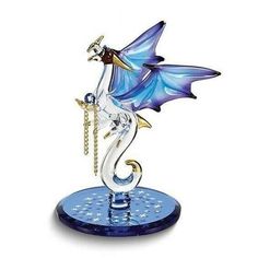 a glass figurine with a blue dragon on it's back and wings