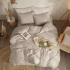 an unmade bed in a bedroom with white walls and wooden floors, along with wicker baskets on the floor