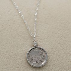 Introducing our exquisite Buffalo/Indian Head Nickel Necklace, a must-have accessory for history buffs, coin collectors, and vintage coin enthusiasts. This timeless piece effortlessly complements both casual and formal wear, making it a versatile addition to your jewelry collection. Featuring an authentic antique Buffalo Nickel from the early 1900s, each necklace tells a unique story of the past. Choose between our sophisticated 18-inch black cord or our elegant 20-inch silver plated braided rope chain, allowing you to customize the necklace to your personal style. Rest assured, every coin used in our necklaces is carefully cleaned before assembly, retaining the coin's original authenticity while enhancing its visual appeal. The bezel mount not only adds a touch of elegance but also serves Silver Necklaces With Coin Pendant For Vintage Collection, Vintage Medallion Coin Pendant Jewelry, Commemorative Coin Pendant Medallion Jewelry, Commemorative Medallion Coin Pendant Jewelry, Antique Medallion Jewelry With Coin Pendant, Vintage Antique Silver Jewelry With Coin Pendant, Nickel Free Medallion Jewelry For Commemoration, Vintage Jewelry With Coin Pendant For Collectors, Heirloom Silver Necklace With Coin Pendant