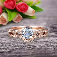 an engagement ring with a blue topaz surrounded by white and pink flowers on a wooden surface