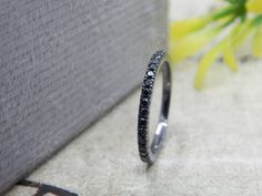 a black diamond ring sitting on top of a table next to a vase with yellow flowers