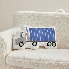 a white couch with a blue and gray truck pillow sitting on it's back