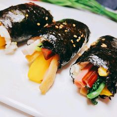 two sushi rolls on a white plate with sesame seeds