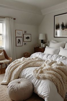 a bed with white sheets and blankets on top of it in a bedroom next to a window