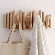 a tote bag hanging on the wall next to a coat rack with wooden pegs