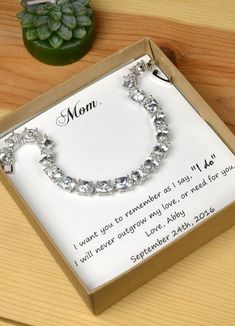 a mother's bracelet is displayed in a box on a table with a plant