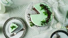 a green cake sitting on top of a white plate next to a knife and fork