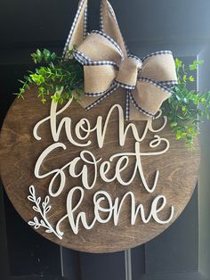 a wooden sign that says home sweet home with a bow hanging on the front door