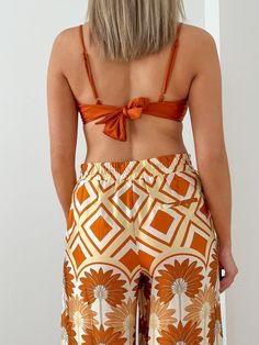 The Blair Sleeveless Tie Back Top his giving off sunny weather vacay vibes all day! This top has adjustable spaghetti straps and a tie back for ease of wear and a shiny mimosa colored fabric that pairs perfectly with the Hawaiian Sunset Kimono and the Hawaiian Sunset Wide Leg Pant for a flirty fun day into night look. Model is 5'10" wearing a size Medium 82% Nylon - 18% Spandex Hand Wash Cold - Do Not Bleach - Hang to Dry