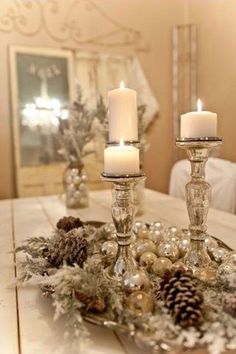 two candles are sitting on a table with pine cones