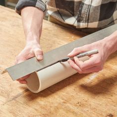 a man is sharpening a piece of paper with a knife on a wooden table