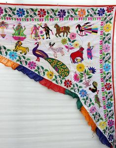 an embroidered table runner with colorful flowers and animals on it, hanging from a wall