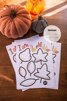 three thanksgiving coloring pages with pumpkins and gourds next to them on a wooden table