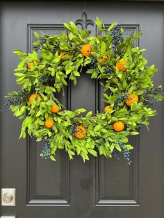 an orange wreath on the front door of a house with blue berries and green leaves