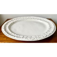 a white platter sitting on top of a wooden table next to a vase and potted plant