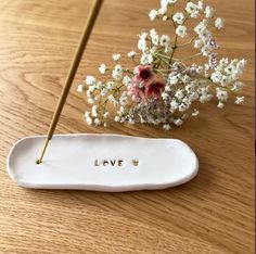 a vase with flowers and writing on it sitting next to a stick that says love