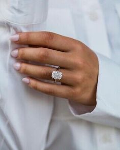 a woman wearing a white shirt and diamond ring on her left hand, holding onto the other