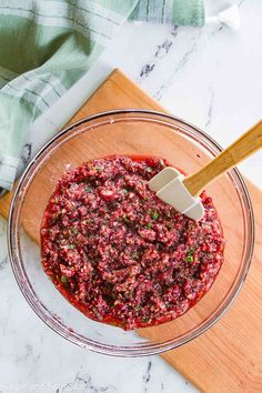 a glass bowl filled with cranberry sauce on top of a wooden cutting board