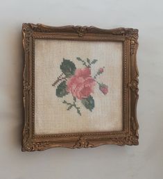 a cross stitch picture frame with a pink rose on it's left hand side