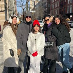 a group of people standing next to each other on a sidewalk in the winter time