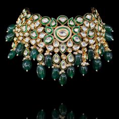 An awe-inspiring ensemble that is sure to turn heads and draw admirers! The look includes a necklace and a pair of earrings exuding pure beauty and refinement with handset kundan stones and beautiful emerald beads. Approximate earrings length is 1". Gold-plated on high-quality brass as base metal. Made by order. Kindly allow 5-7 weeks for the delivery of this item. For custom or urgent requests, please contact support@alacouture.com. *Please Note: We use faux stones and beads in all of our jewel Fusion Kundan Bridal Necklace With Jewels, Traditional Emerald Kundan Necklace For Formal Occasions, Formal Kundan Necklace With Jeweled Details, Jeweled Kundan Necklace For Formal Occasions, Green Kundan Necklace For Formal Occasions, Festive Kundan Emerald Necklace For Receptions, Formal Jeweled Kundan Necklace, Formal Green Kundan Necklace, Festive Emerald Kundan Chandbali Necklace