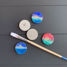 three different colored discs and a brush on a table with some other items around them