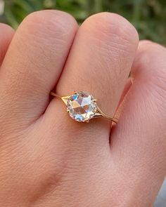 a woman's hand holding a ring with an oval shaped diamond in the middle