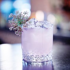 a purple drink sitting on top of a table next to a glass filled with ice