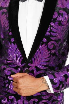 a man in a purple and black suit with his hand on his lapel pocket