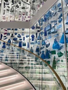 there are many glass items on display in the building's stairwell area, including blue dresses and umbrellas