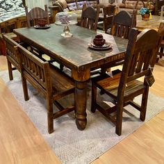 a wooden table with chairs around it in a room filled with couches and tables