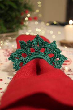 a green brooch sitting on top of a red napkin next to a lit candle