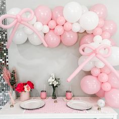 a table topped with plates and pink balloons