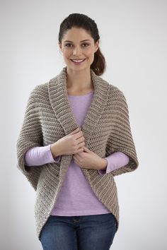 a woman is smiling and wearing a knitted cardigan sweater over her purple shirt