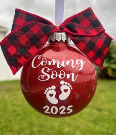 a red ornament hanging from the side of a tree with a bow on it